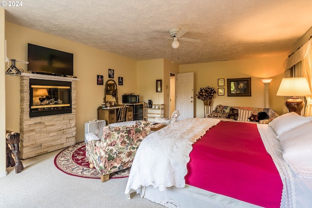 carpeted bedroom featuring ceiling fan, a textured ceiling, and a fireplace