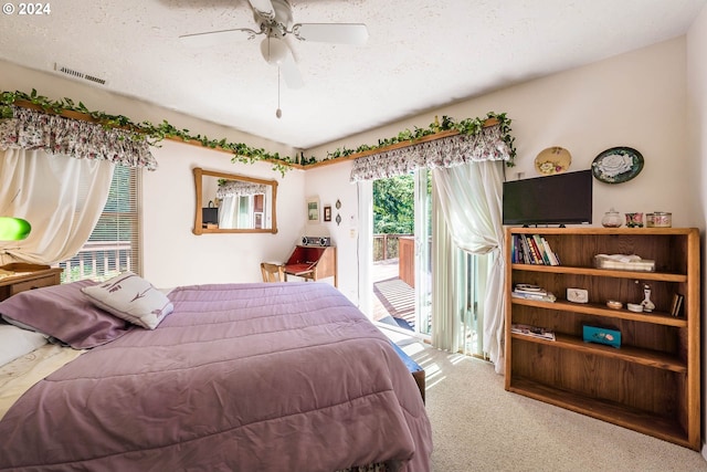 carpeted bedroom with ceiling fan, access to exterior, and a textured ceiling