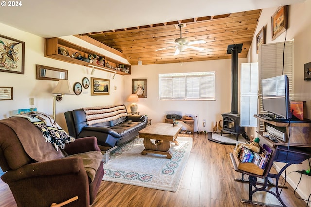 living room with lofted ceiling, wooden ceiling, a wood stove, hardwood / wood-style flooring, and ceiling fan