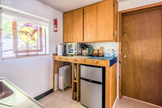 kitchen featuring radiator heating unit, stainless steel appliances, and light tile patterned flooring