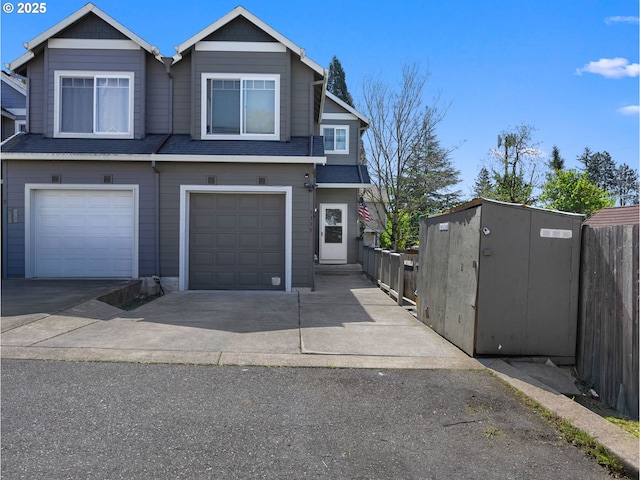 multi unit property featuring concrete driveway, fence, and a garage