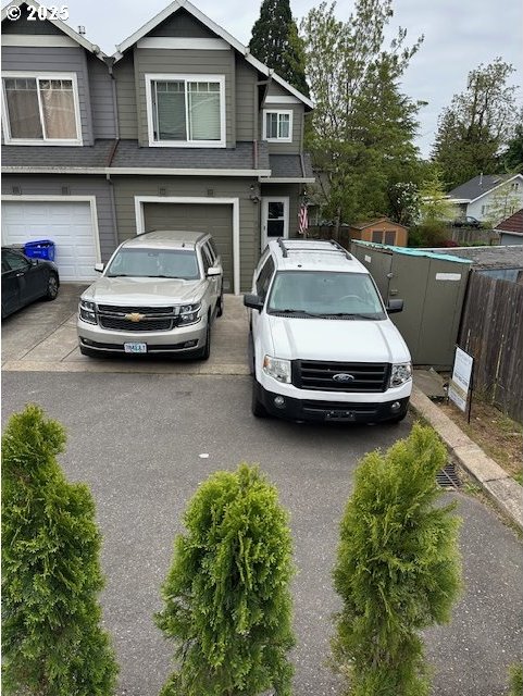 view of front facade featuring fence, a garage, and aphalt driveway