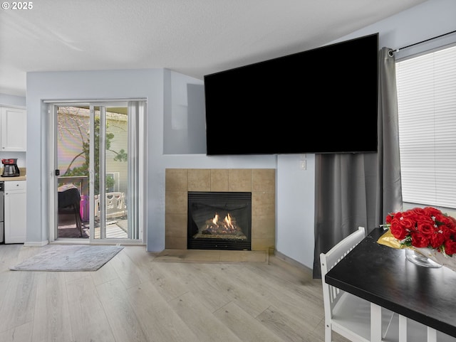 living area featuring a tile fireplace and light wood-style floors