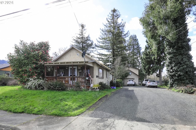 view of front of property with covered porch, a garage, and a front lawn