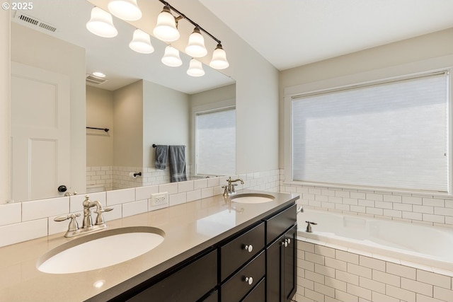 bathroom featuring visible vents, a sink, a garden tub, and double vanity