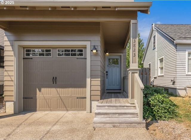 view of exterior entry with a garage and concrete driveway