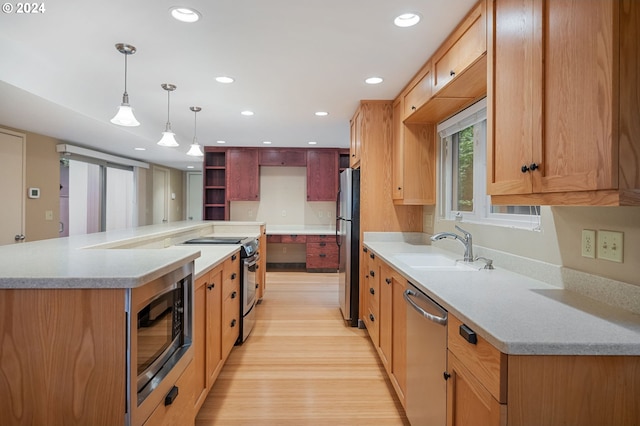 kitchen with appliances with stainless steel finishes, sink, light wood-type flooring, and light stone counters