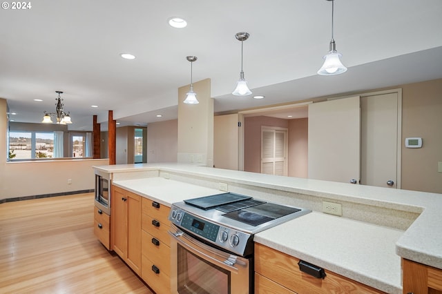 kitchen with an inviting chandelier, light wood-type flooring, stainless steel appliances, decorative light fixtures, and light stone counters