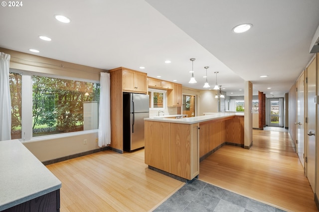 kitchen featuring plenty of natural light, a kitchen island, light hardwood / wood-style floors, and stainless steel refrigerator