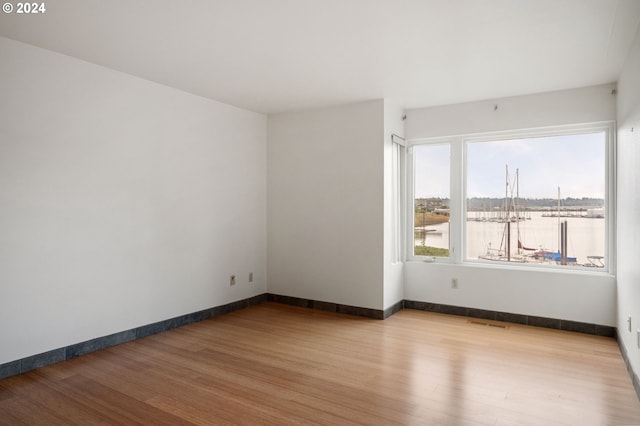 unfurnished room featuring a water view and light wood-type flooring