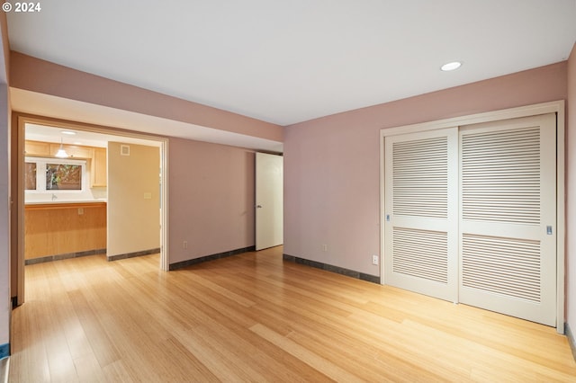 unfurnished bedroom with connected bathroom, light hardwood / wood-style flooring, and a closet