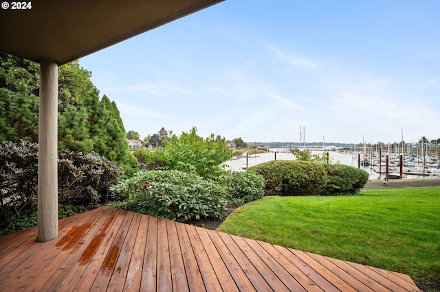 wooden terrace featuring a water view and a lawn