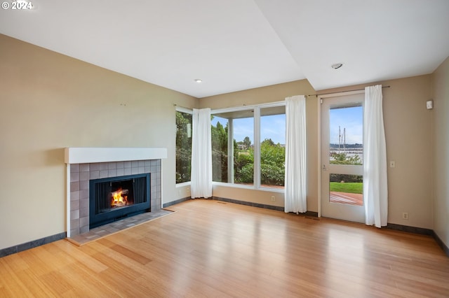 549 N Tomahawk Island Dr # 1, Portland, OR 97217 - unfurnished living room with a tiled fireplace, a healthy amount of sunlight, baseboards, and wood finished floors