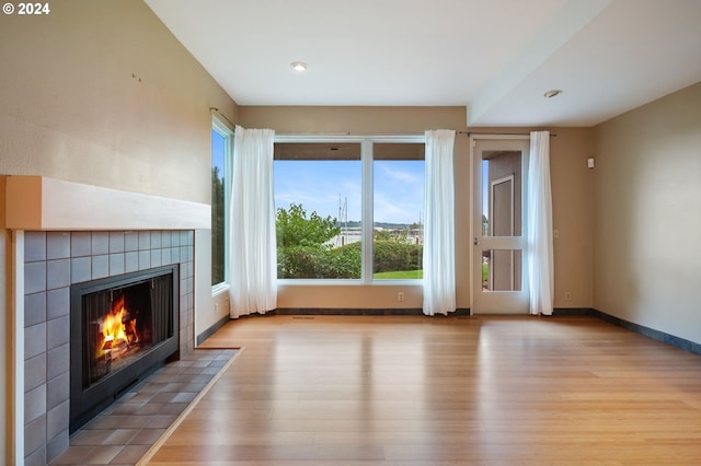 unfurnished living room featuring light wood-type flooring and a tile fireplace