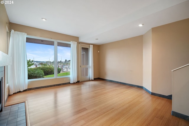 unfurnished room featuring a tile fireplace and light wood-type flooring