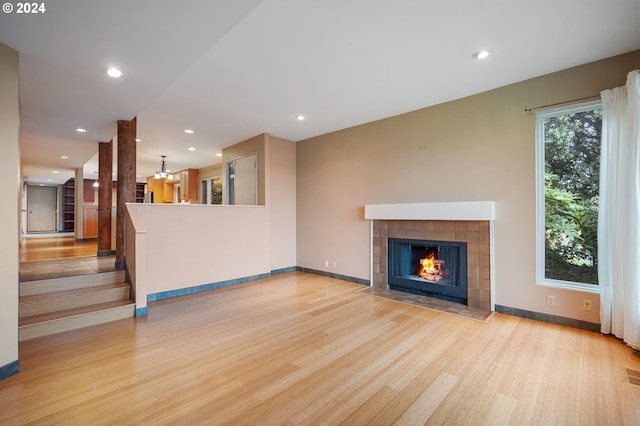 unfurnished living room with light hardwood / wood-style floors, plenty of natural light, and a tile fireplace