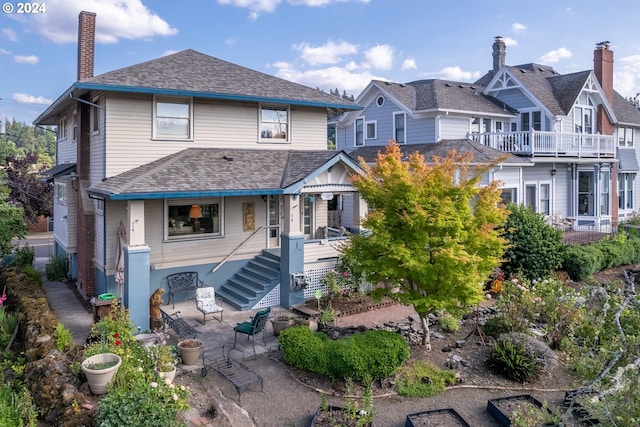 rear view of house featuring a shingled roof, a residential view, a patio area, and a chimney