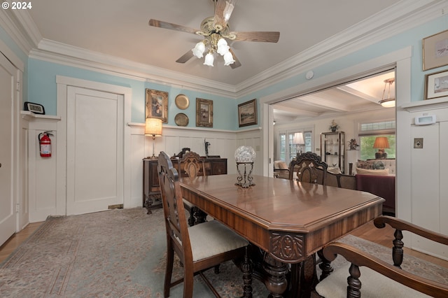 dining space featuring a decorative wall, a ceiling fan, and crown molding