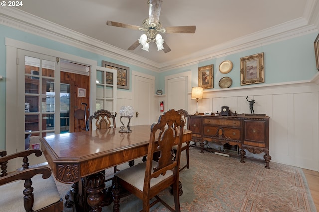 dining room featuring ceiling fan, ornamental molding, and a decorative wall