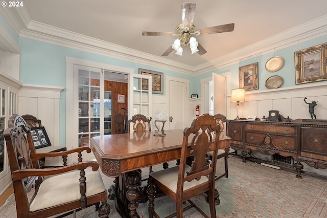 dining room featuring crown molding, wainscoting, a decorative wall, and a ceiling fan