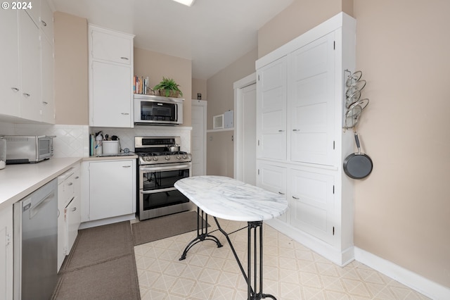 kitchen featuring baseboards, stainless steel appliances, light countertops, white cabinetry, and backsplash