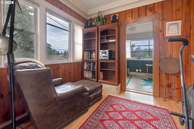 living area featuring ornamental molding, wood walls, and light wood-style flooring