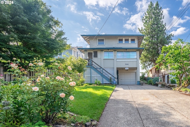 raised beach house featuring driveway, a garage, stairway, and a front lawn