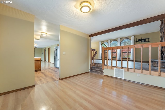 unfurnished room with a textured ceiling and light hardwood / wood-style floors