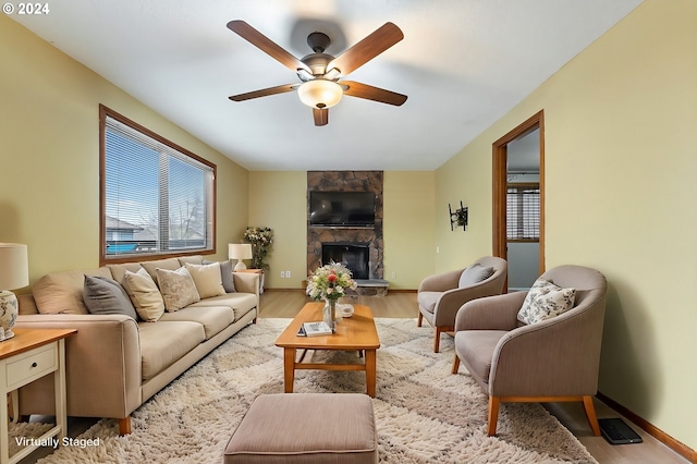 living room featuring a fireplace, light wood-type flooring, and ceiling fan