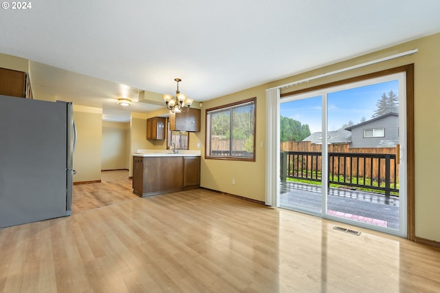 kitchen with pendant lighting, light hardwood / wood-style flooring, stainless steel refrigerator, and an inviting chandelier