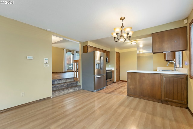 kitchen featuring sink, hanging light fixtures, light hardwood / wood-style flooring, kitchen peninsula, and appliances with stainless steel finishes