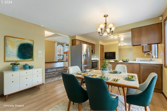 dining area featuring an inviting chandelier, ornamental molding, sink, and light hardwood / wood-style flooring