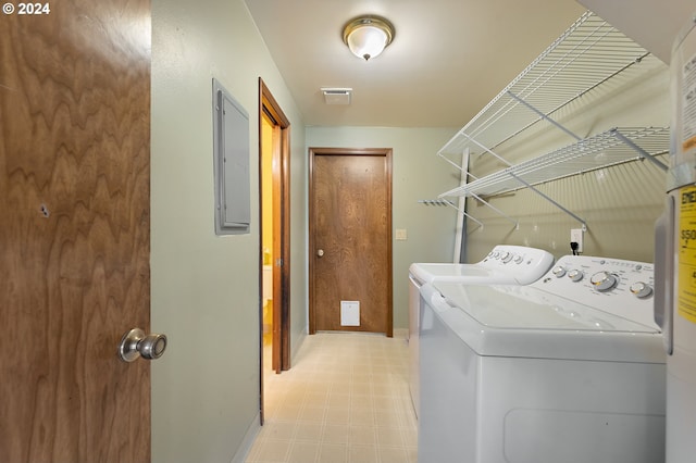 clothes washing area with independent washer and dryer, electric panel, and water heater