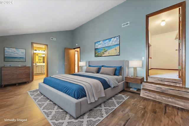 bedroom featuring ensuite bathroom, lofted ceiling, and hardwood / wood-style flooring