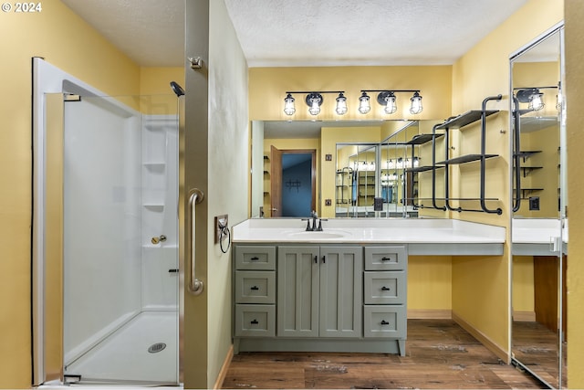 bathroom featuring a textured ceiling, vanity, wood-type flooring, and an enclosed shower