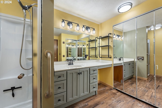 bathroom featuring walk in shower, vanity, a textured ceiling, and hardwood / wood-style flooring