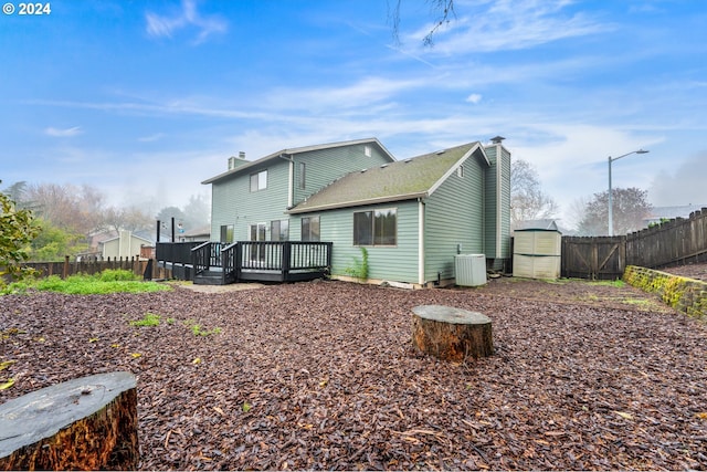 back of house with cooling unit, a shed, and a wooden deck