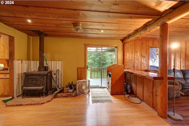 interior space featuring wood ceiling, a wood stove, beam ceiling, wooden walls, and light wood-type flooring