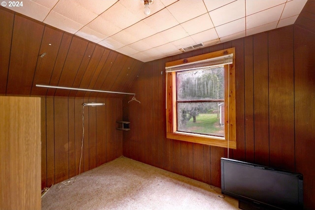 additional living space with lofted ceiling, wooden walls, and light carpet