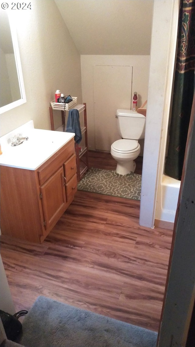 full bathroom featuring tub / shower combination, vanity, wood-type flooring, vaulted ceiling, and toilet