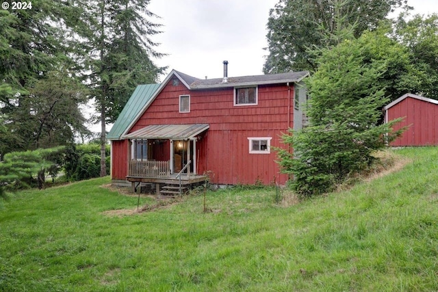 rear view of house featuring a storage shed and a yard