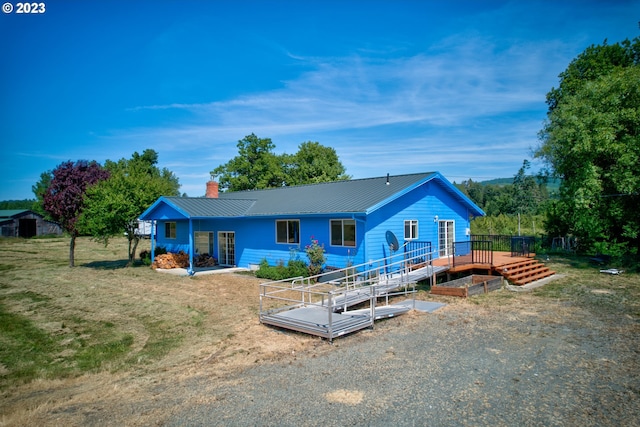 ranch-style home with a wooden deck and a front lawn