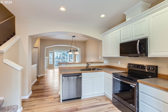 kitchen featuring sink, stainless steel appliances, white cabinets, and pendant lighting