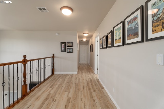 corridor with light wood-type flooring, baseboards, and visible vents