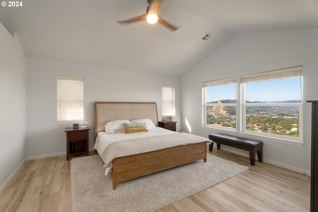 bedroom with light wood-style floors, lofted ceiling, visible vents, and baseboards