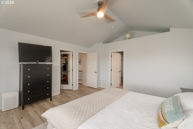 bedroom with lofted ceiling, ceiling fan, a walk in closet, and light wood-style floors