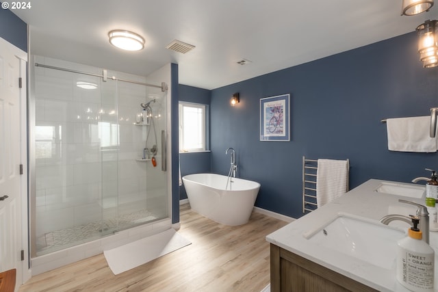 bathroom with a freestanding tub, visible vents, a sink, and wood finished floors