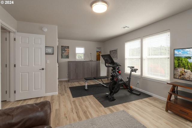 workout room featuring light wood-type flooring, plenty of natural light, visible vents, and baseboards