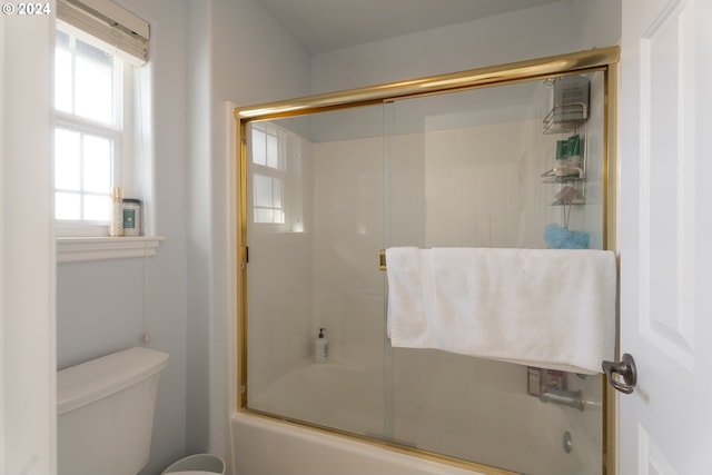 bathroom with bath / shower combo with glass door and toilet