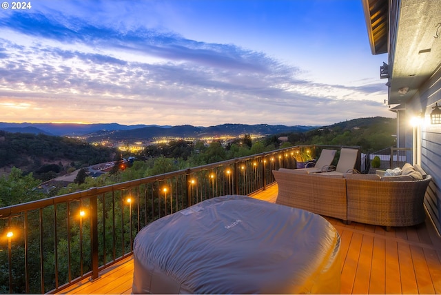 balcony at dusk featuring a mountain view and an outdoor hangout area